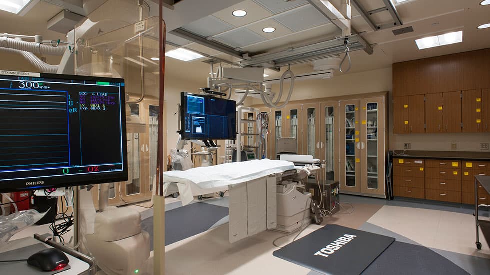 Electrophysiology (EP) lab with a ceiling-mounted imaging system, cardiac monitors, and isolated power wired by H&M Electric