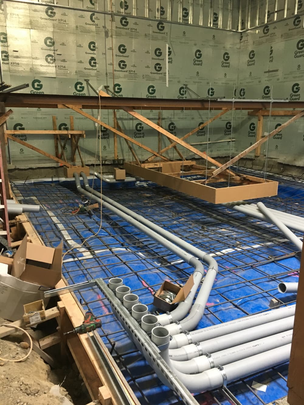 Banks of underground electrical conduit rough-in sweeping through rebar for a radiation oncology linear accelerator (LINAC) vault